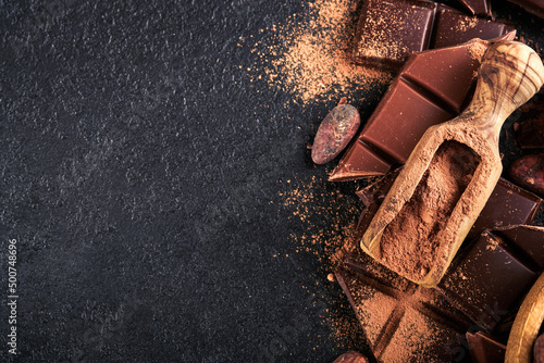 Chocolate and cocoa powder. Composition of cocoa powder, grated and bean cocoa bars and pieces of different milk and dark chocolate on black background. Baking Chocolate Texture. Top view. Mock up.