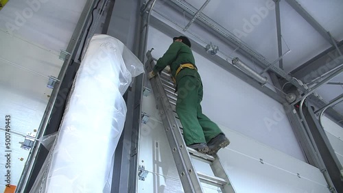 Professional worker climbing up ladder indoors to repair a transformer. Man in a workwear