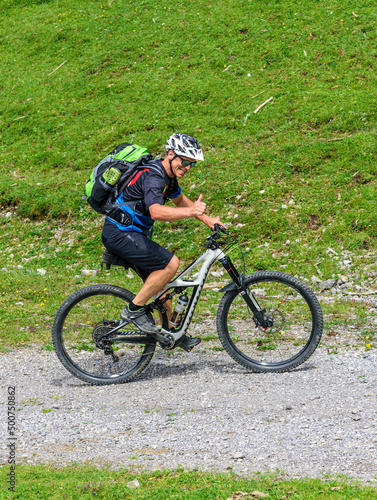 Sportlicher Mountainbiker hat Spaß trotz anstrengendem Anstieg im Gebirge