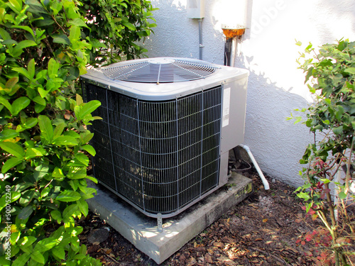 Air Conditioning Unit On Side of Florida House with Green Bushes