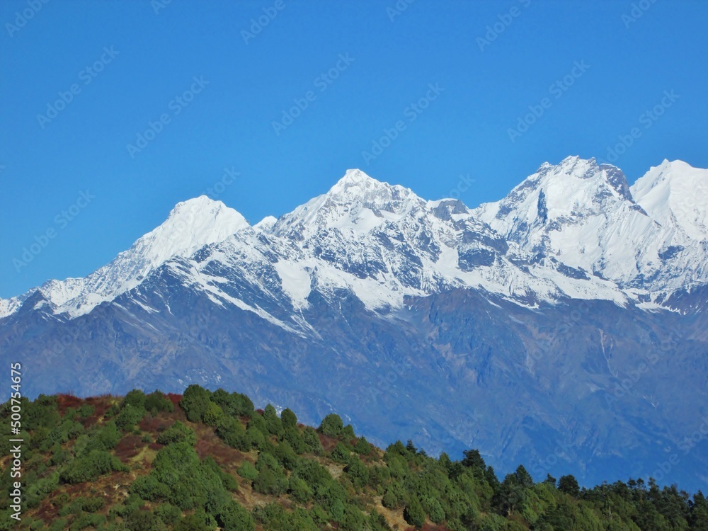 Panorama of Himalaya mountains and trees in Nepal. Langtang National Park. Trekking in Nepal. Peaks covered with snow against the blue sky. Holiday destination. Relaxing views. Panorama of Himalaya mountains and trees in Nepal. Langtang National Park. Trekking in Nepal. Peaks covered with snow against the blue sky. Holiday destination. Relaxing views.