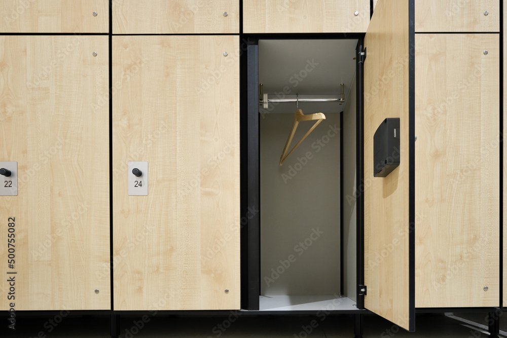 Gym locker room, beige doors with locks. Open door with rack and hanger. Organizing storage concept. Selective focus Gym locker room, beige doors with locks. Open door with rack and hanger. Organizing storage concept. Selective focus