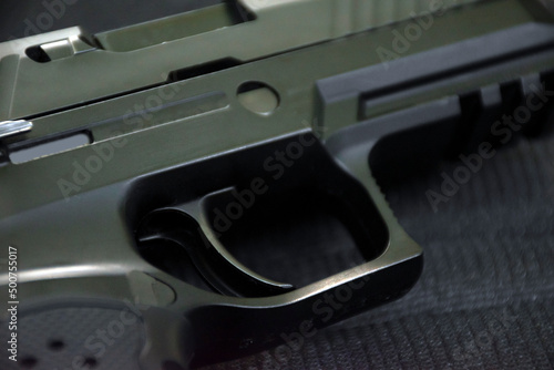 Automatic 9mm pistol gun on black leather background, soft and selective focus.