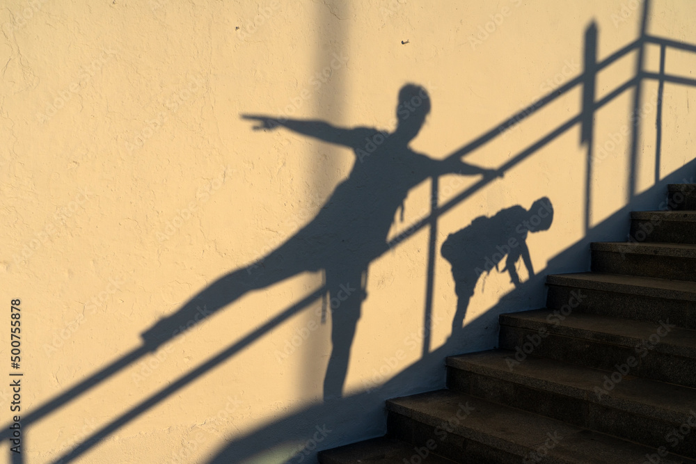 Shadows of a happy mother and son playing with different postures against a wall at sunset