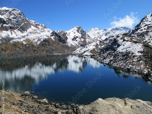 Mountain landscape. Astounding view of Gosaikunda Lake. Himalayas against the cloudy sky. Beautiful Day in the mountains. Peaks reflection in the Water. Gosainkunda in Langtang National Park, Nepal