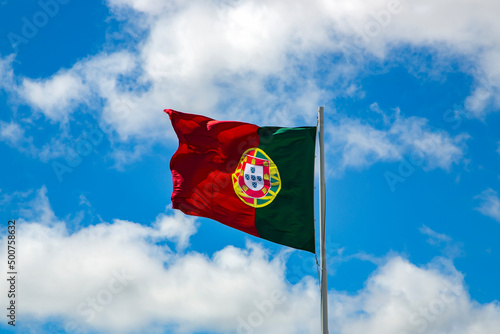 Portuguese national flag waving on blue sky background. Blue sky with beautiful clouds.
