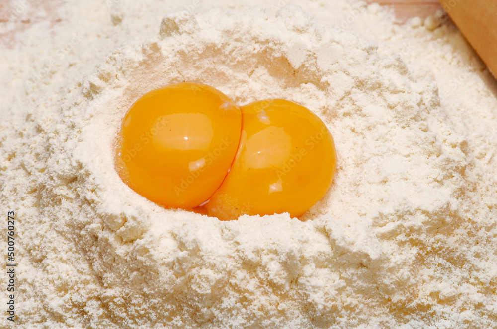 Yellow Egg on fresh flour on kitchen table background.. Yellow Egg on fresh flour on kitchen table background..