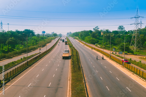 A landscape of highway with both side green trees, going through cites with transports. 