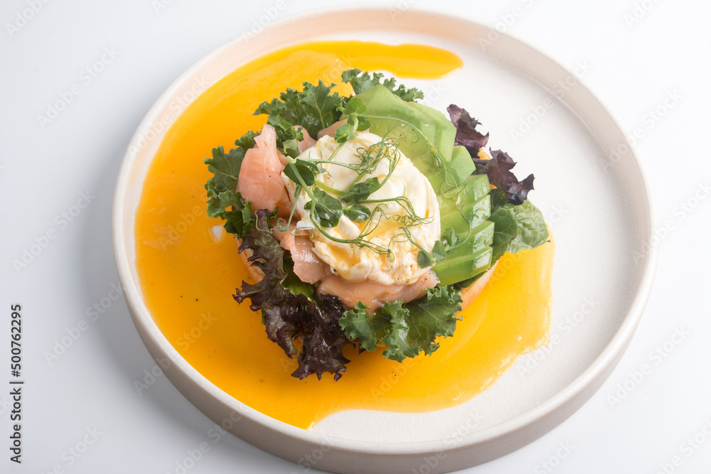 restaurant dish Brioche with poached egg with salmon and avocado. Delicious bread with greens restaurant dish Brioche with poached egg with salmon and avocado. Delicious bread with greens
