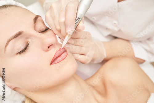 Permanent makeup. Beauty spa procedure. young woman. Face tattoo. Lip micropigmentation. Professional face microblading. Female cosmetology device. Copyspace. Mouth treatment. Dermatology