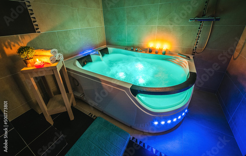 Illuminated massage bath with water. Luxury bathroom. Burning candles.