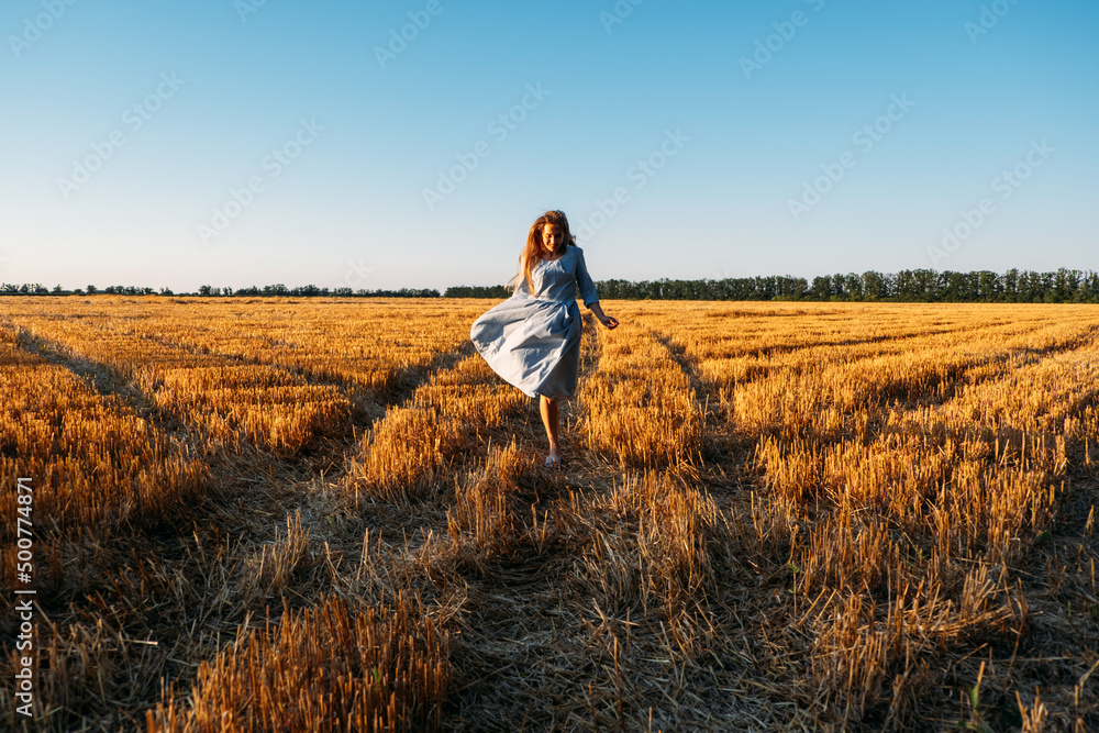 Woman in blue linen dress enjoying nature in sunset field. Stress and psychological resilience. Spend Time in Nature to Reduce Stress and Anxiety. Woman in blue linen dress enjoying nature in sunset field. Stress and psychological resilience. Spend Time in Nature to Reduce Stress and Anxiety.