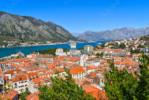Kotor, Montenegro, Europe. Bay of Kotor on Adriatic Sea. Roofs of the historical buildings in the old town, sea and mountains in the background. Clear blue sky, sunny day