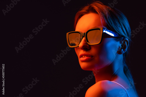 young woman adjusting sunglasses and posing isolated on purple