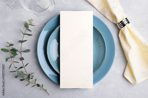 Vertical menu card mockup with festive wedding or birthday table setting, eucalyptus, blue ceramic plate on grey background. Empty blank card mock up. Restaurant menu concept. Flat lay, top view