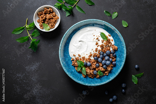 Chocolate granola with white plain yogurt and fresh blueberry in a bowl, healthy food for breakfast, top view photo