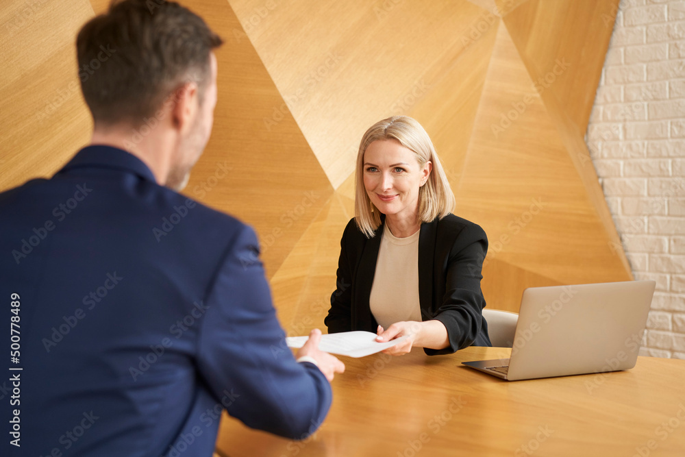 Recruiter passing agreement to new employee at modern office Recruiter passing agreement to new employee at modern office