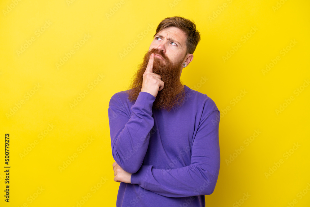 Redhead man with beard isolated on yellow background having doubts while looking up Redhead man with beard isolated on yellow background having doubts while looking up