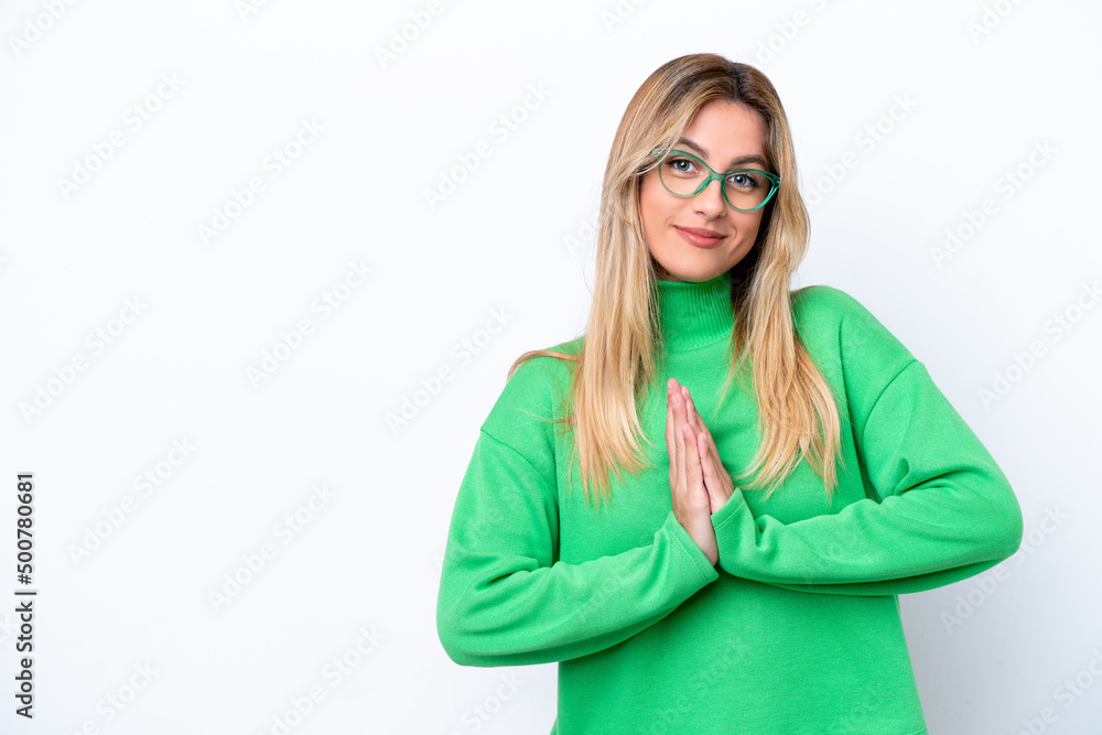 Young Uruguayan woman isolated on white background keeps palm together. Person asks for something
