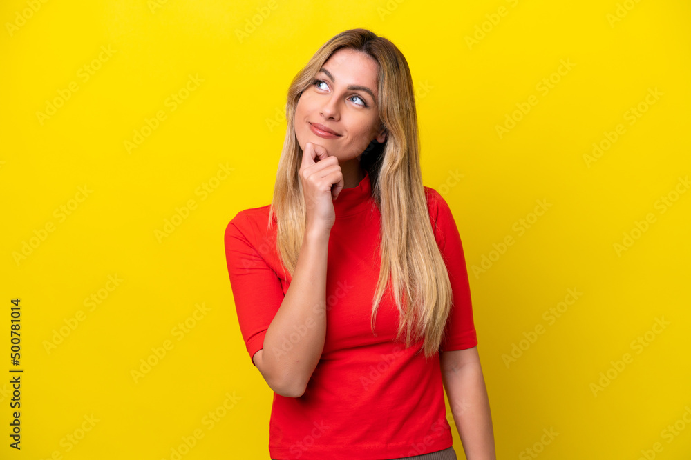 Young Uruguayan woman isolated on yellow background and looking up Young Uruguayan woman isolated on yellow background and looking up