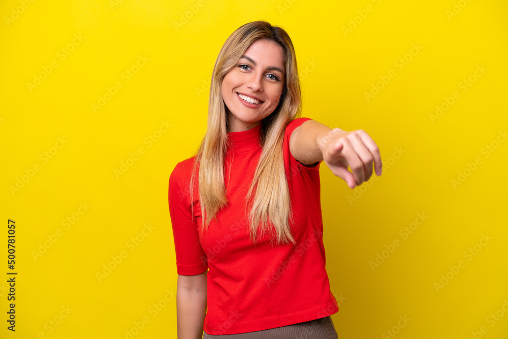 Young Uruguayan woman isolated on yellow background pointing front with happy expression Young Uruguayan woman isolated on yellow background pointing front with happy expression