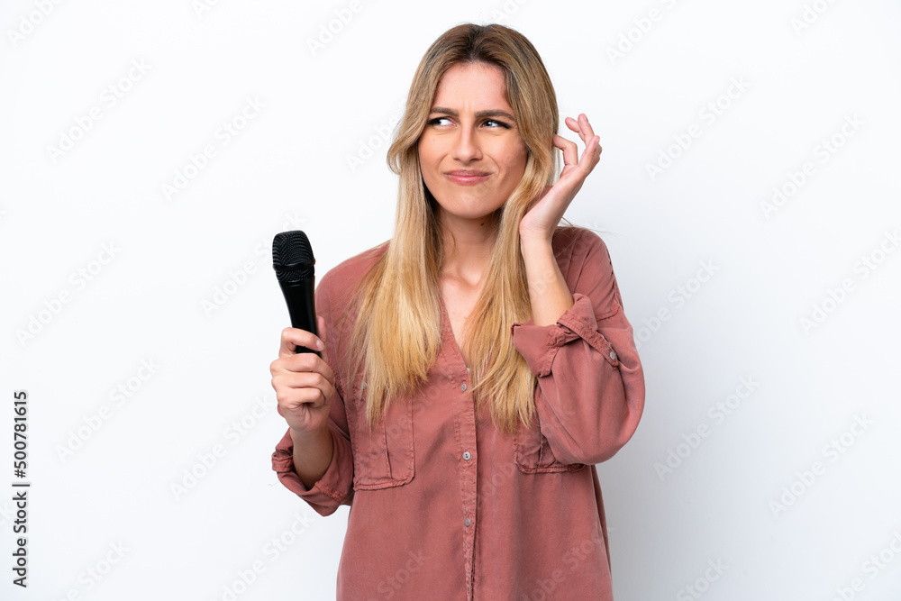 Singer Uruguayan woman picking up a microphone isolated on white background frustrated and covering ears Singer Uruguayan woman picking up a microphone isolated on white background frustrated and covering ears