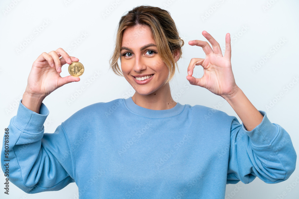 Fototapeta premium Young Uruguayan woman holding a Bitcoin isolated on white background showing ok sign with fingers