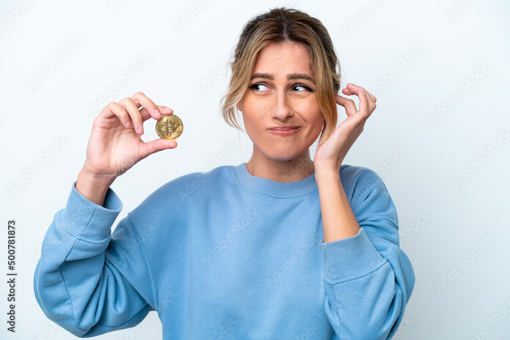 Fototapeta premium Young Uruguayan woman holding a Bitcoin isolated on white background frustrated and covering ears