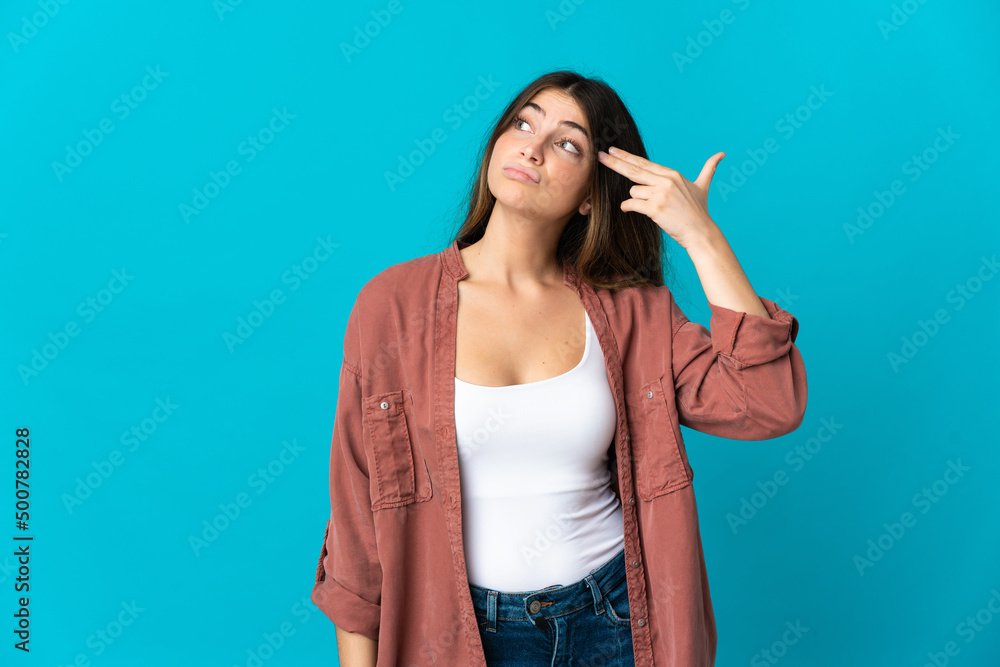 Young caucasian woman isolated on blue background with problems making suicide gesture Young caucasian woman isolated on blue background with problems making suicide gesture