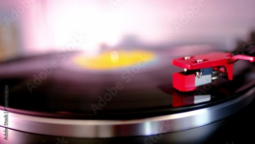 close-up of black vinyl record, disk is spinning, colored lights, analogue retro music concept, audio experience, relaxation, musical enjoyment, vintage technology, nostalgia for the past photo
