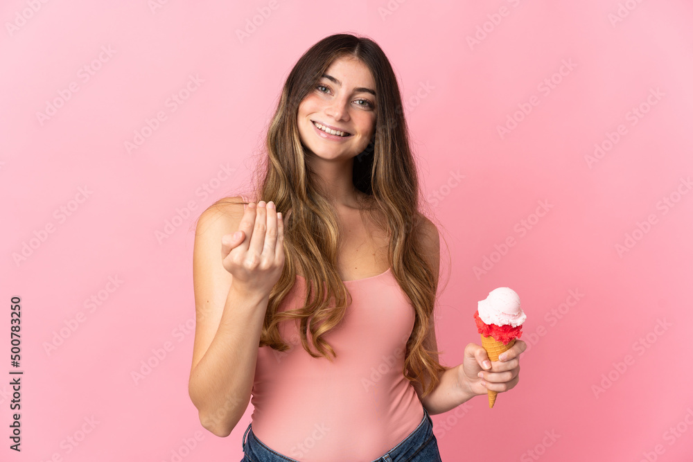Young caucasian woman with a cornet ice cream isolated on pink background inviting to come with hand. Happy that you came Young caucasian woman with a cornet ice cream isolated on pink background inviting to come with hand. Happy that you came