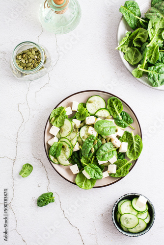 Fresh salad of cucumbers, spinach, cheese and pumpkin seeds in a plate. Top and vertical view