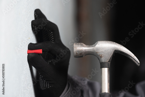 Worker inserts a plastic dowel into the wall close up. photo