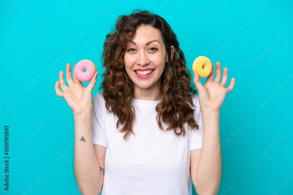 Young caucasian woman isolated on blue background holding donuts Young caucasian woman isolated on blue background holding donuts