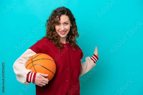Young caucasian basketball player woman isolated on blue background extending hands to the side for inviting to come © luismolinero