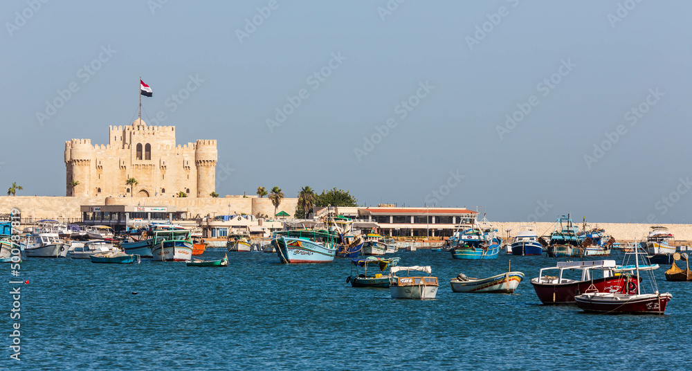 Alexandria, Egypt - January 2022: Citadel of Qaitbay across the Eastern Harbour and boats in the water