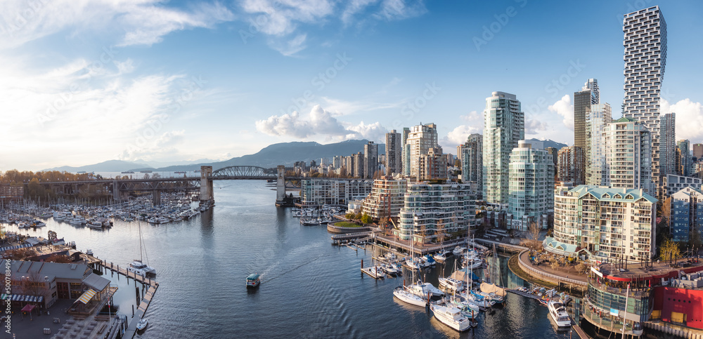 Fototapeta premium Panoramic Aerial View of Granville Island in False Creek with modern city skyline and mountains in background. Downtown Vancouver, British Columbia, Canada.