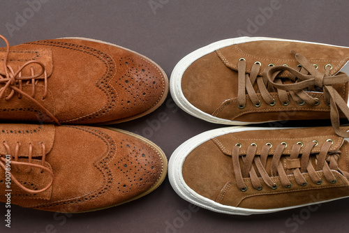 Print op canvas Pair of brown suede derby shoes vs beige sneakers on brown background