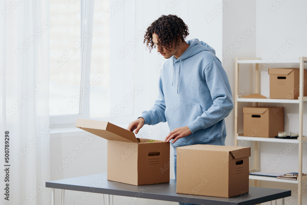 portrait of a man in headphones unpacking with box in hand Lifestyle portrait of a man in headphones unpacking with box in hand Lifestyle