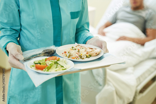 Medical person keeping tray with food in hospital