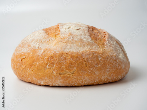 A close-up of a whole fresh crispy delicious round-shaped wheat bread on a white background. Insulated items, baking, side vew