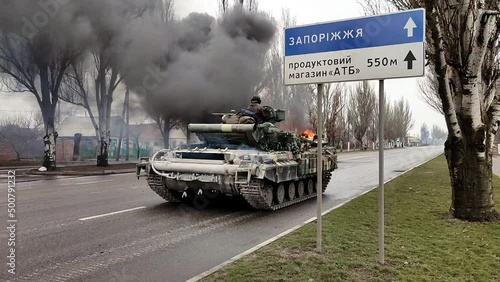 Ukraine armed forces tank drives along street while war machine burns in city. War in Ukraine. photo