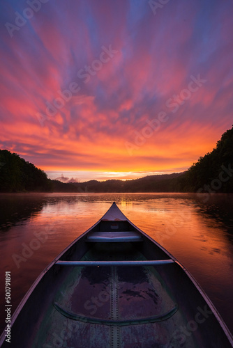 Slika na platnu Colorful sunset after passing storm from an old aluminum canoe on mountain lake