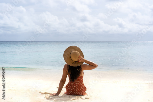 Young girl from the back in a straw hat on the background of the sea bay