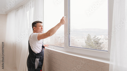 a repairman repairs, adjusts or installs metal-plastic windows in the apartment.