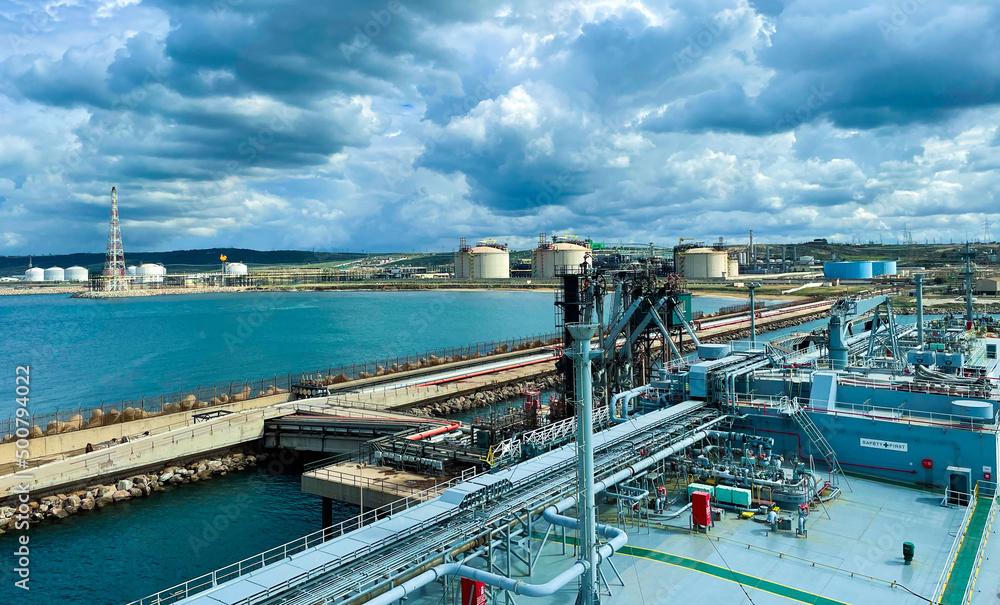 Fototapeta premium LPG cargo ship docked in the port. View from the deck of the ship to the shore and gas tanks