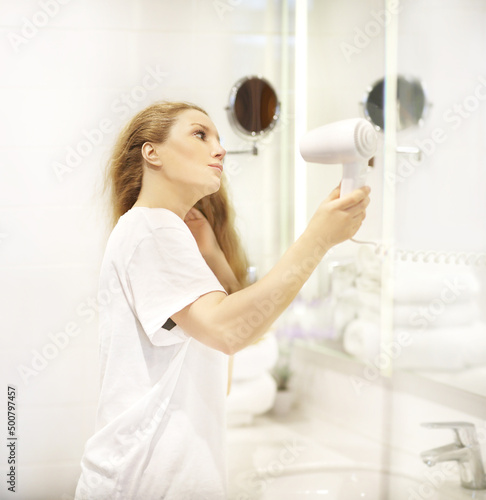 woman in the bathroom drying her hair with a hairdryer