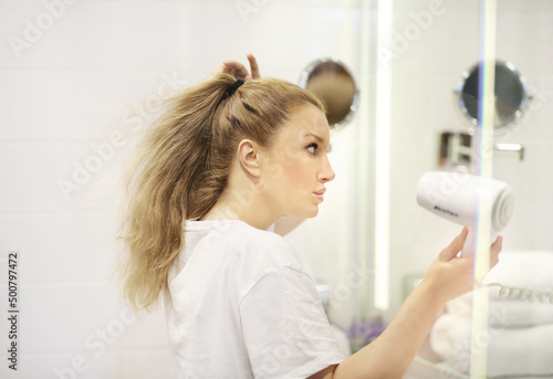 woman in the bathroom drying her hair with a hairdryer