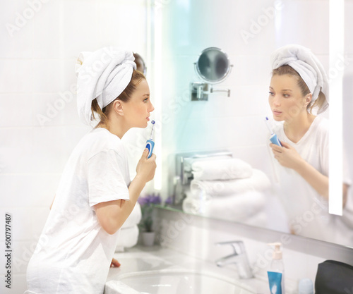 Middle-aged woman in the bathroom taking a shower, applying cream and brushing her teeth