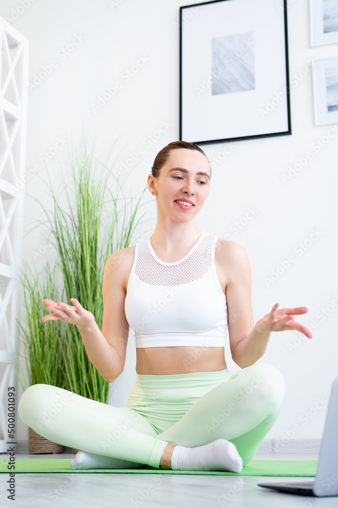 Fitness coach. Workout class. Sporty leisure. Cheerful healthy fit woman instructor doing gymnastics course online at laptop on yoga mat at home. Fitness coach. Workout class. Sporty leisure. Cheerful healthy fit woman instructor doing gymnastics course online at laptop on yoga mat at home.